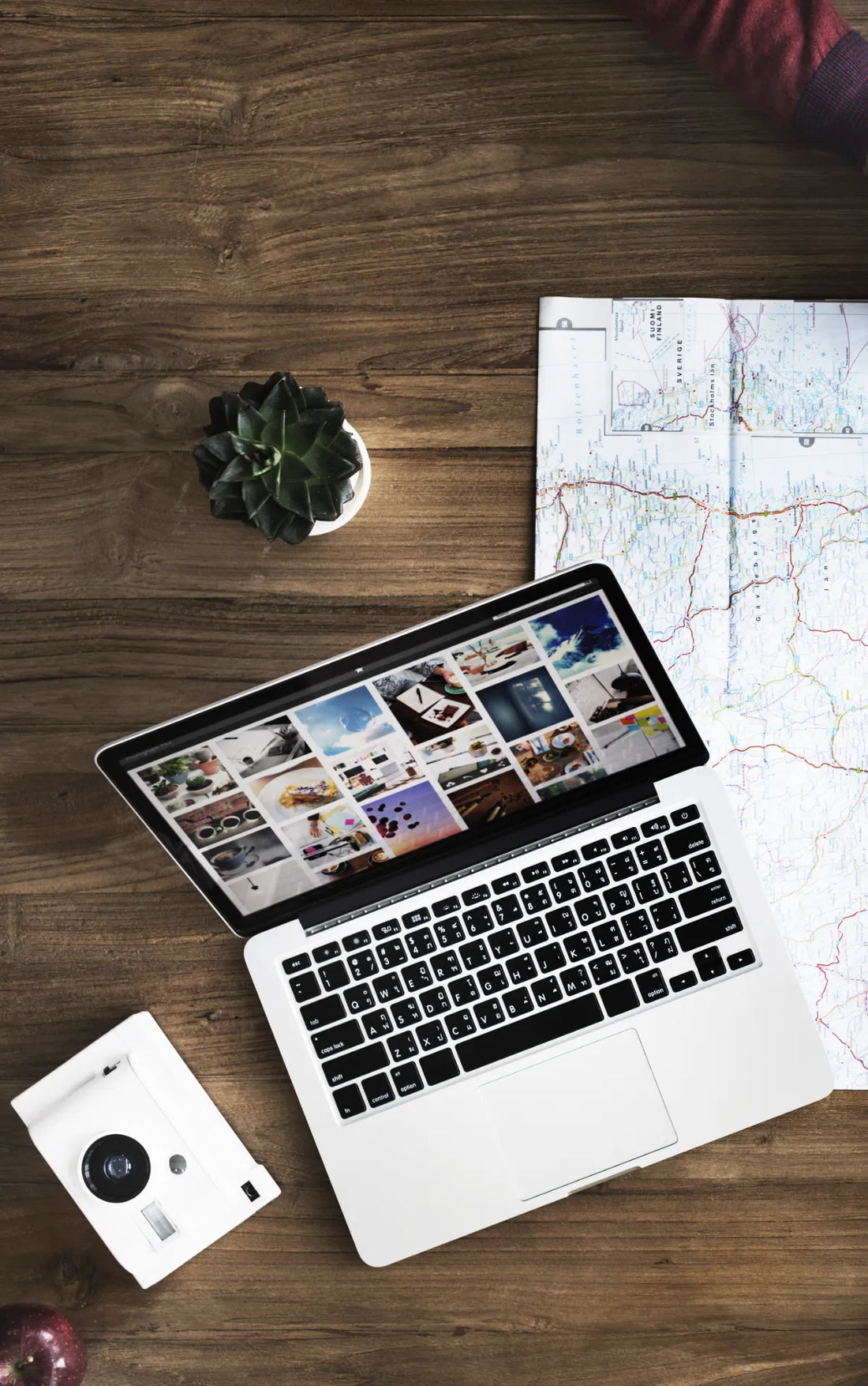 un ordinateur posé sur un bureau en bois qui affiche un site avec des images style pinterest