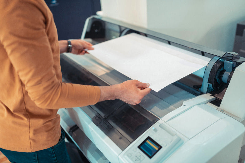 un homme utilise un traceur pour imprimer une affiche grand format
